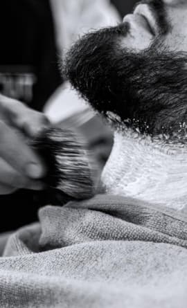 A barber is shaving a client