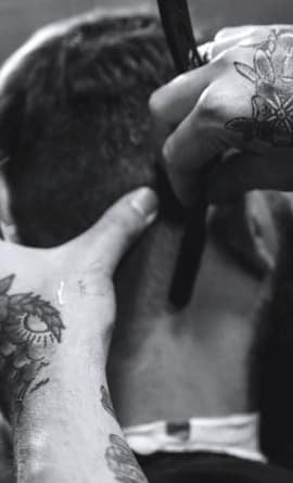 A barber is shaving a client