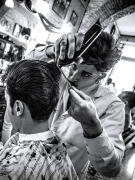 The barber is cutting a client