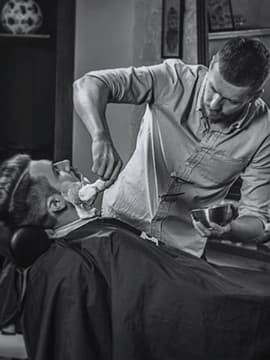 The barber is shaving a client