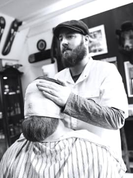 The barber is shaving a client